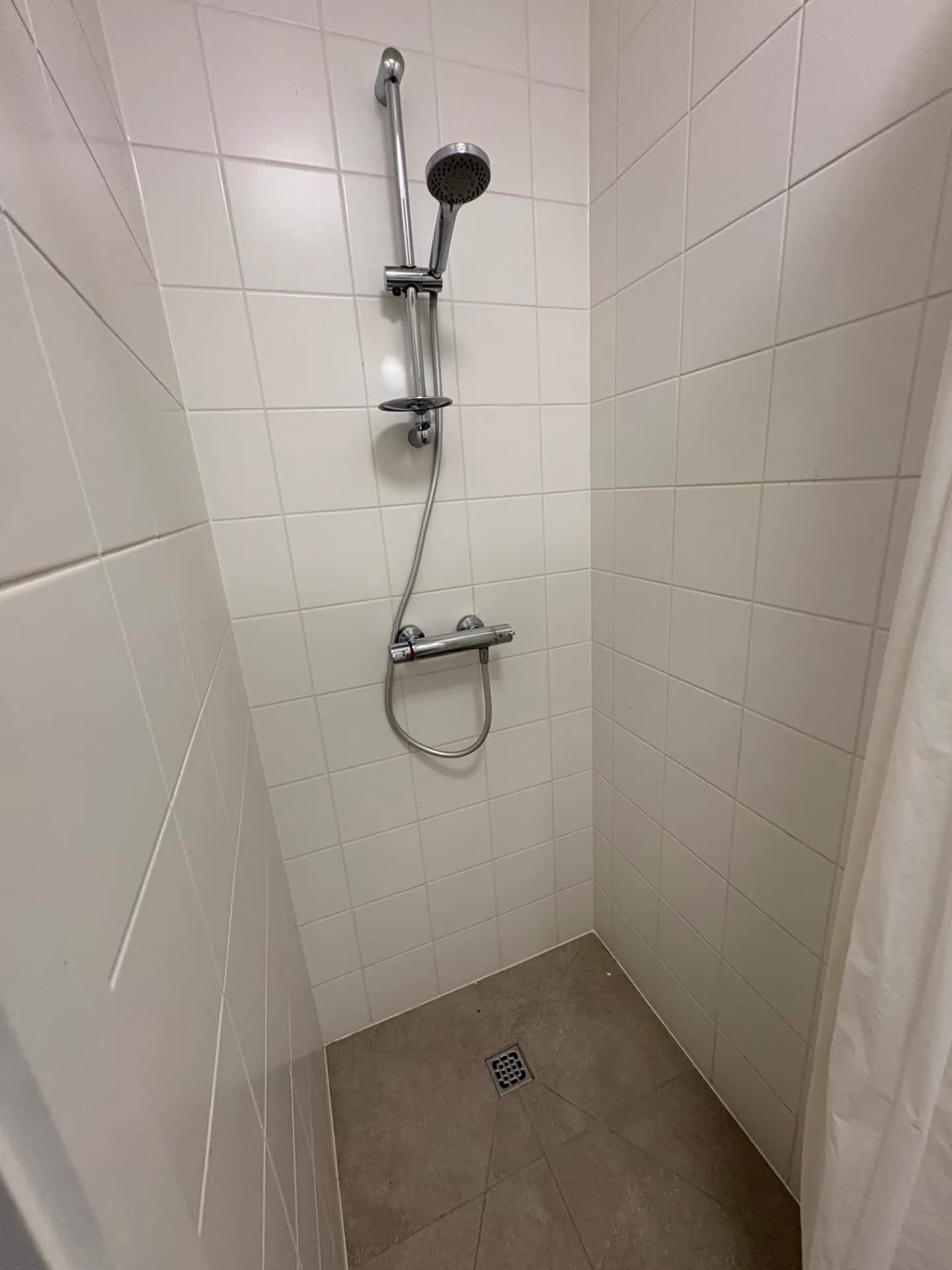 Douche met gereinigde tegels, voegen en afvoerzone